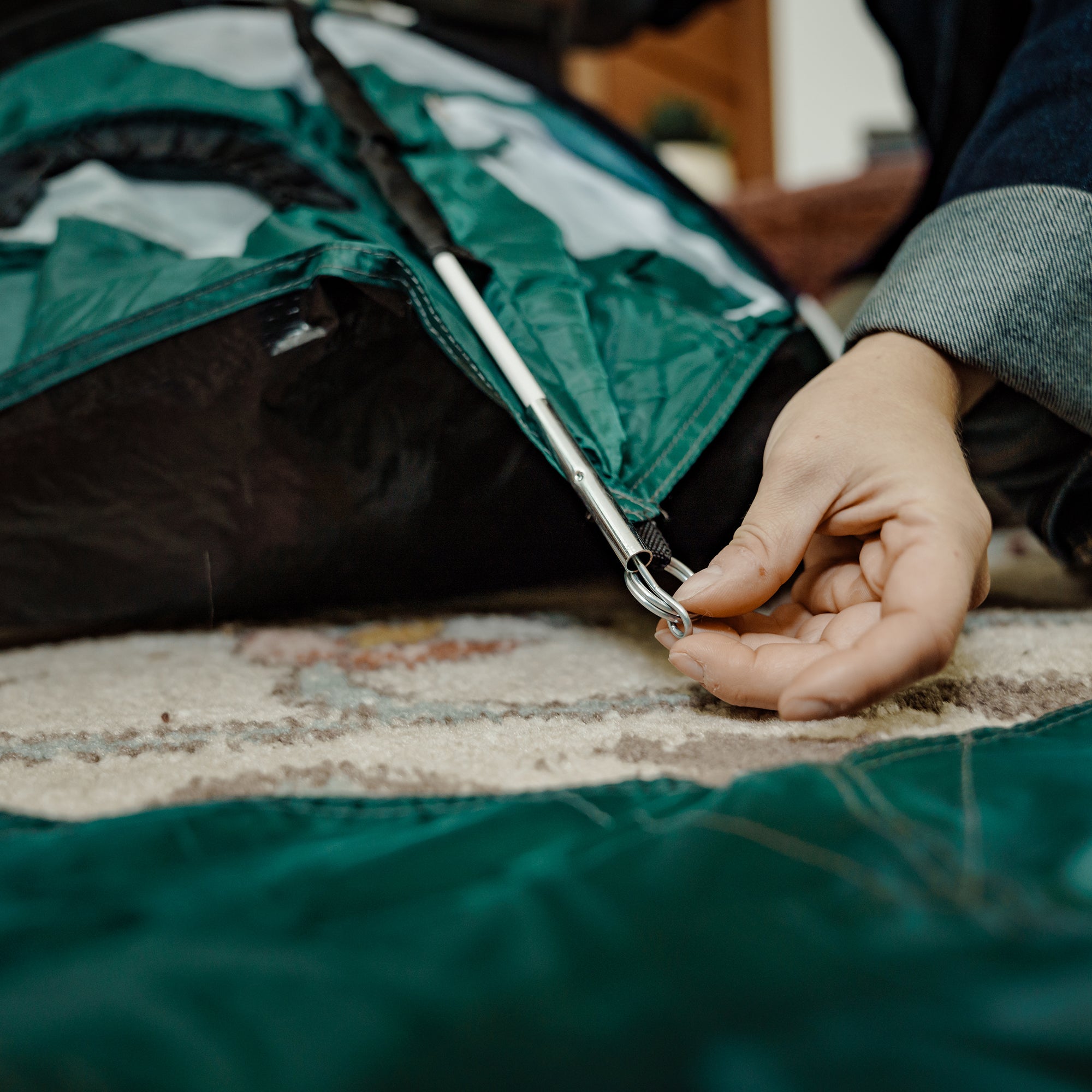 Hands placing tiny tent rainfly into tent pole