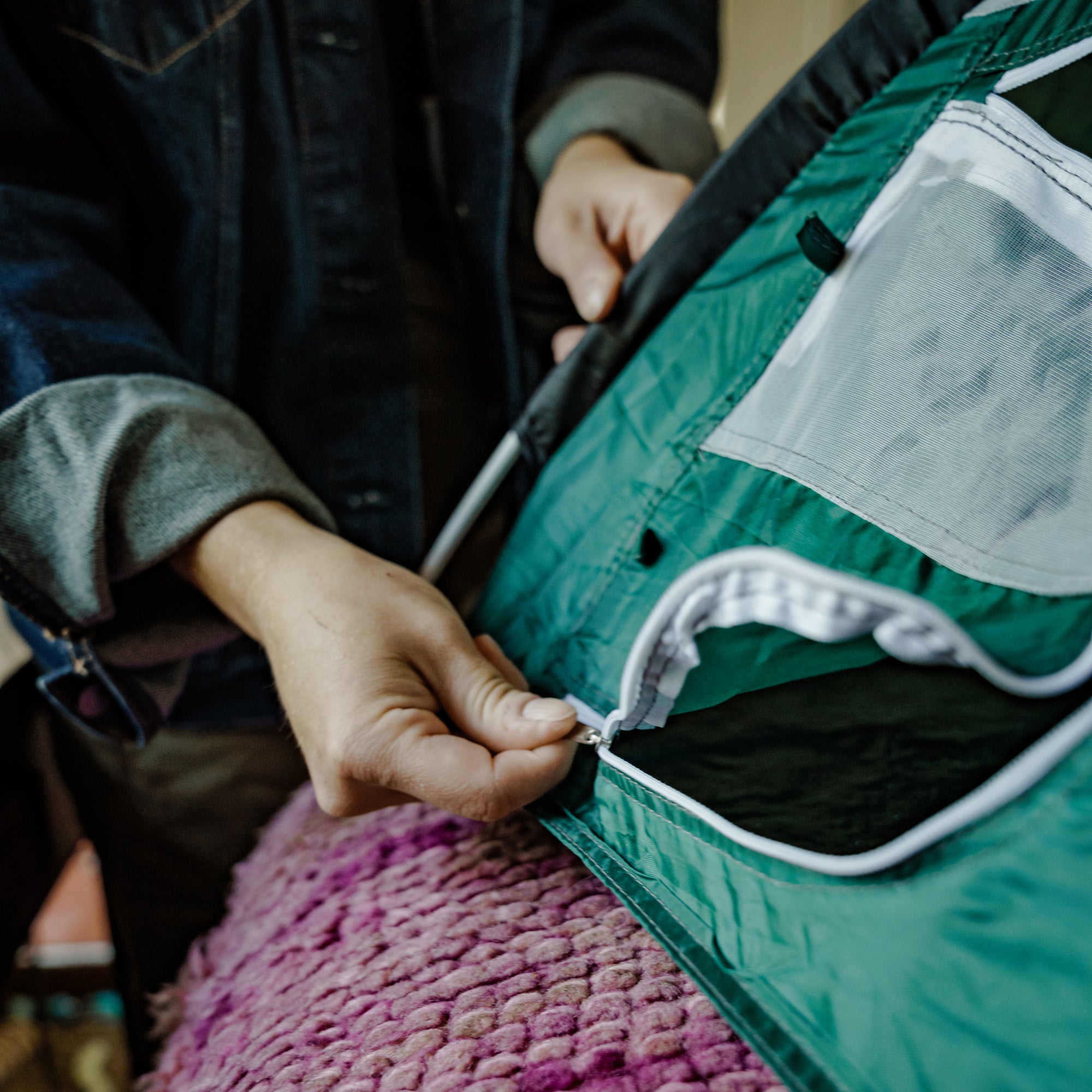 Hands zipping up the entry flap of green tiny tent