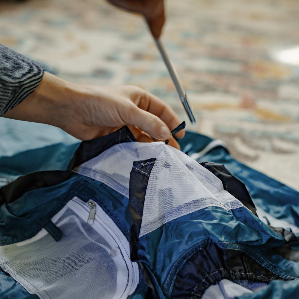 Blue tiny tent being assembled. User is inserting a pole into one of the pole sleeves.