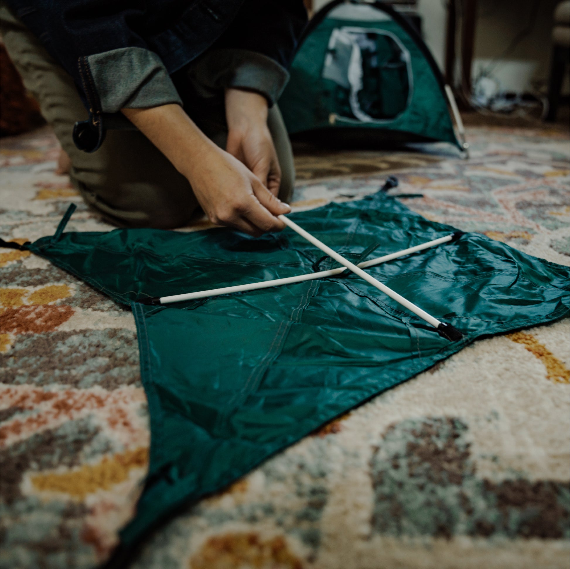 Green tiny tent rainfly being assembled.