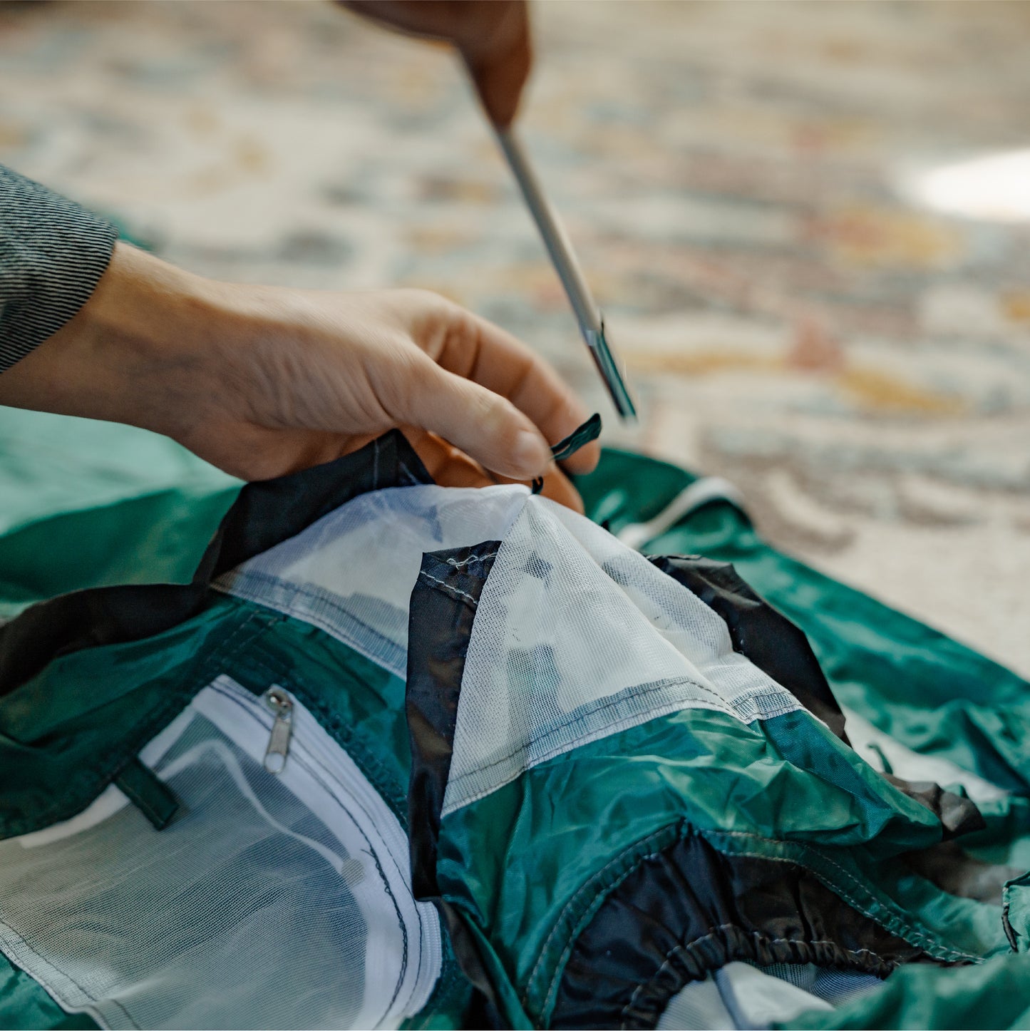 green tiny tent being assembled.  User is inserting a pole into the tent pole slot.