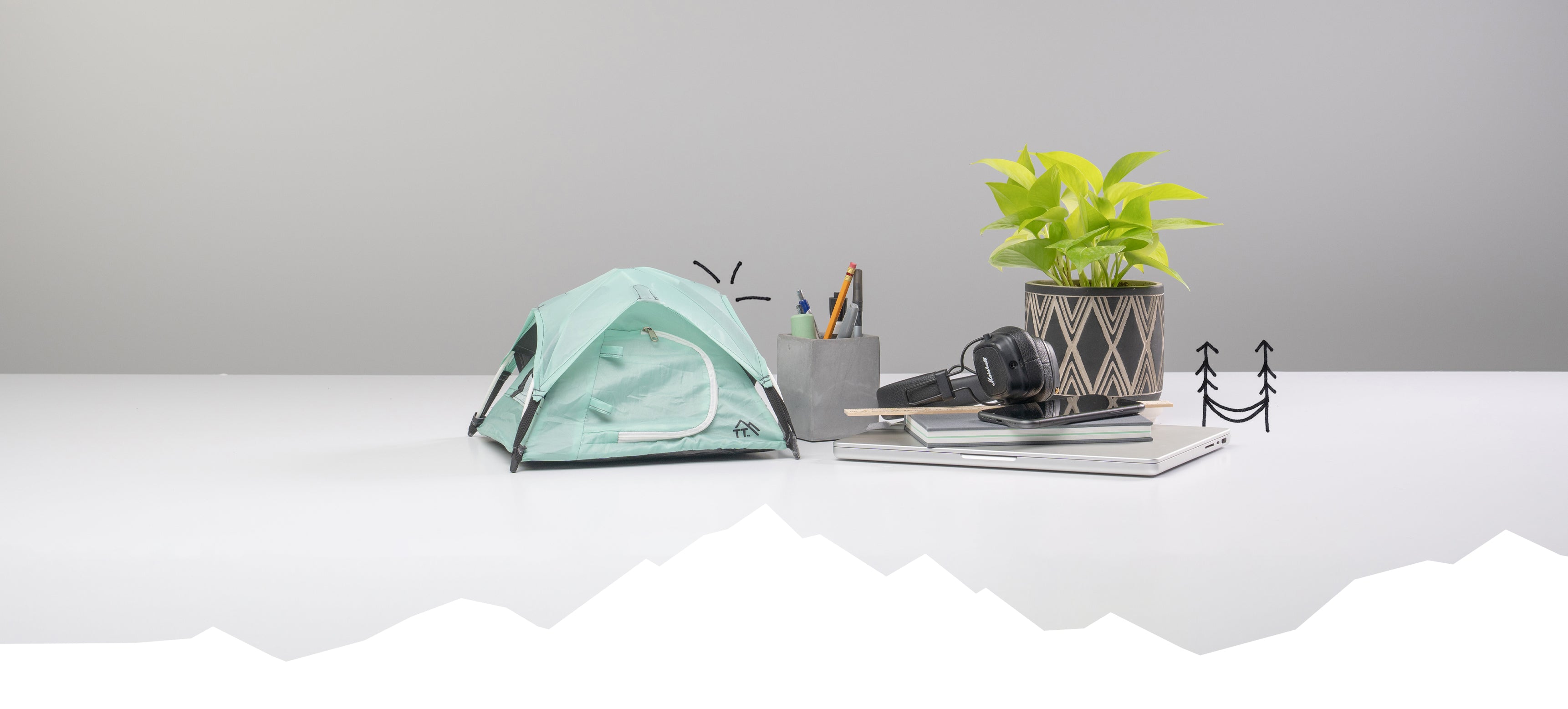 mint colored micro tent with office supplies: pen holder, headphones, potted plant, and computer