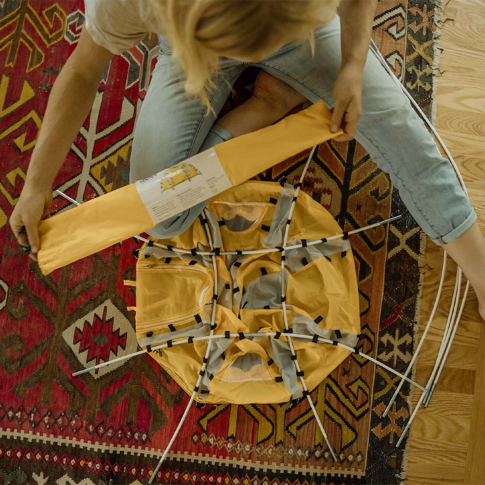 Woman sitting on floor, assembling dome tent